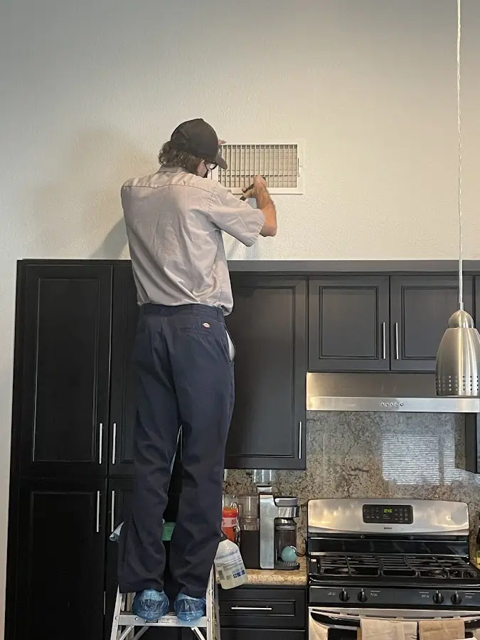Technician inspecting an air vent during HVAC service in North Auburn